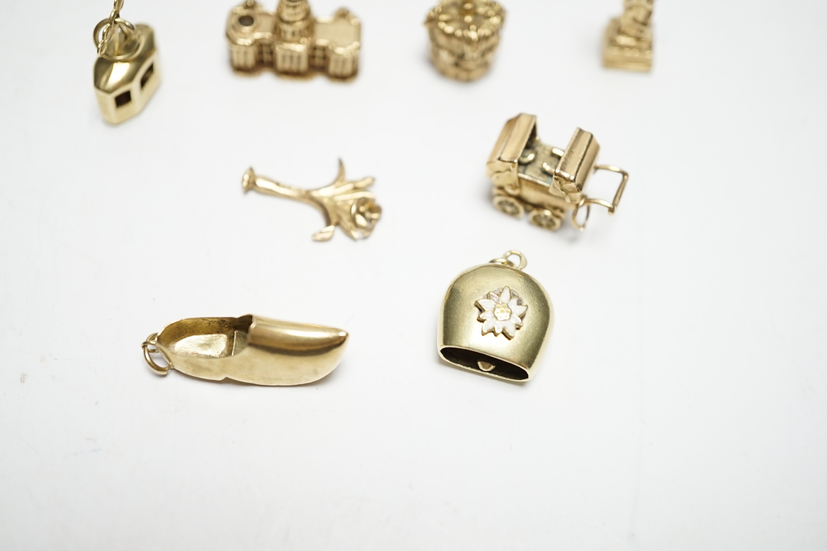 A 585 'Cable car' charm, 1.4 grams, three 9ct gold charms, 9.9 grams and four other yellow metal charms, one with enamel, gross weight 12.5 grams.
